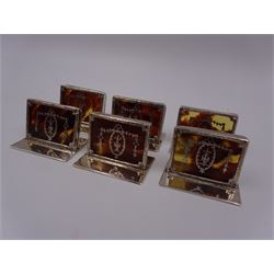 Set of six early 20th century silver mounted tortoiseshell place card holders by Asprey, the rectangular silver reed and ribbon frame bordering a central tortoiseshell panel inlaid with a silver floral motif, upon an oblong foot, hallmarked Asprey & Co Ltd, London 1913, H3cm, contained within a tooled leather fitted case with velvet and silk lined interior 