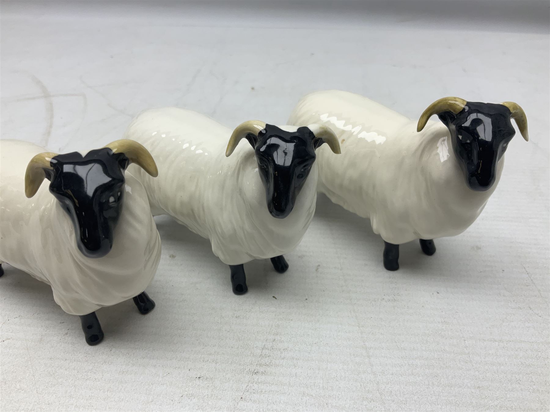 Seven Beswick figures of sheep comprising three ewes and four lambs, together with a figure of a sheepdog (8)