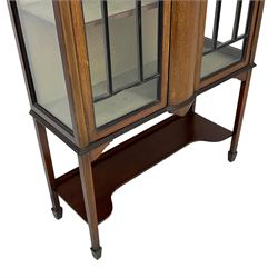 Edwardian inlaid mahogany display cabinet, enclosed by two astragal glazed doors, bowed centre inlaid with ribbon and trailing bellflowers, on square tapering supports with spade feet united by undertier 