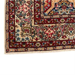 Central Persian Kirman carpet, the field arranged with alternating indigo star shaped and red cruciform compartments, each filled with rosettes, flowerheads and scrolling foliage, enclosed by a broad ivory palmette border and red floral guard bands