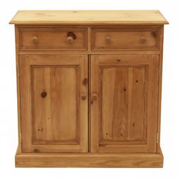Contemporary pine storage cabinet, the rectangular top with rounded corners, over twin drawers and panelled cupboard doors, fitted with turned knob handles, plinth base