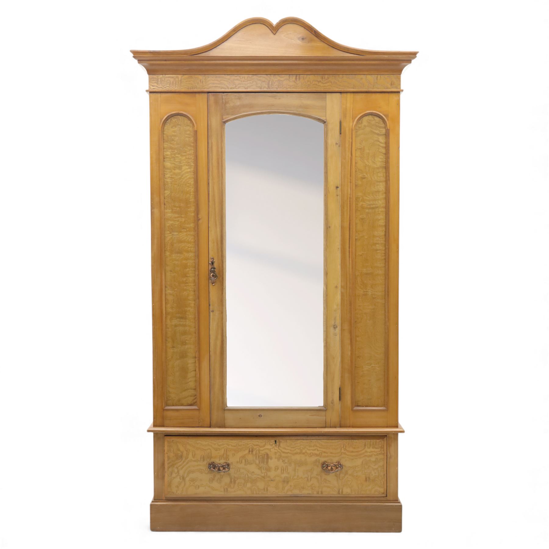 Victorian satin walnut single door wardrobe, shaped cavetto cornice above a central arched mirrored door flanked by recessed panelled sides, the interior fitted with hanging space and later added corner shelves, over a single long drawer with brass handles, on a plinth base