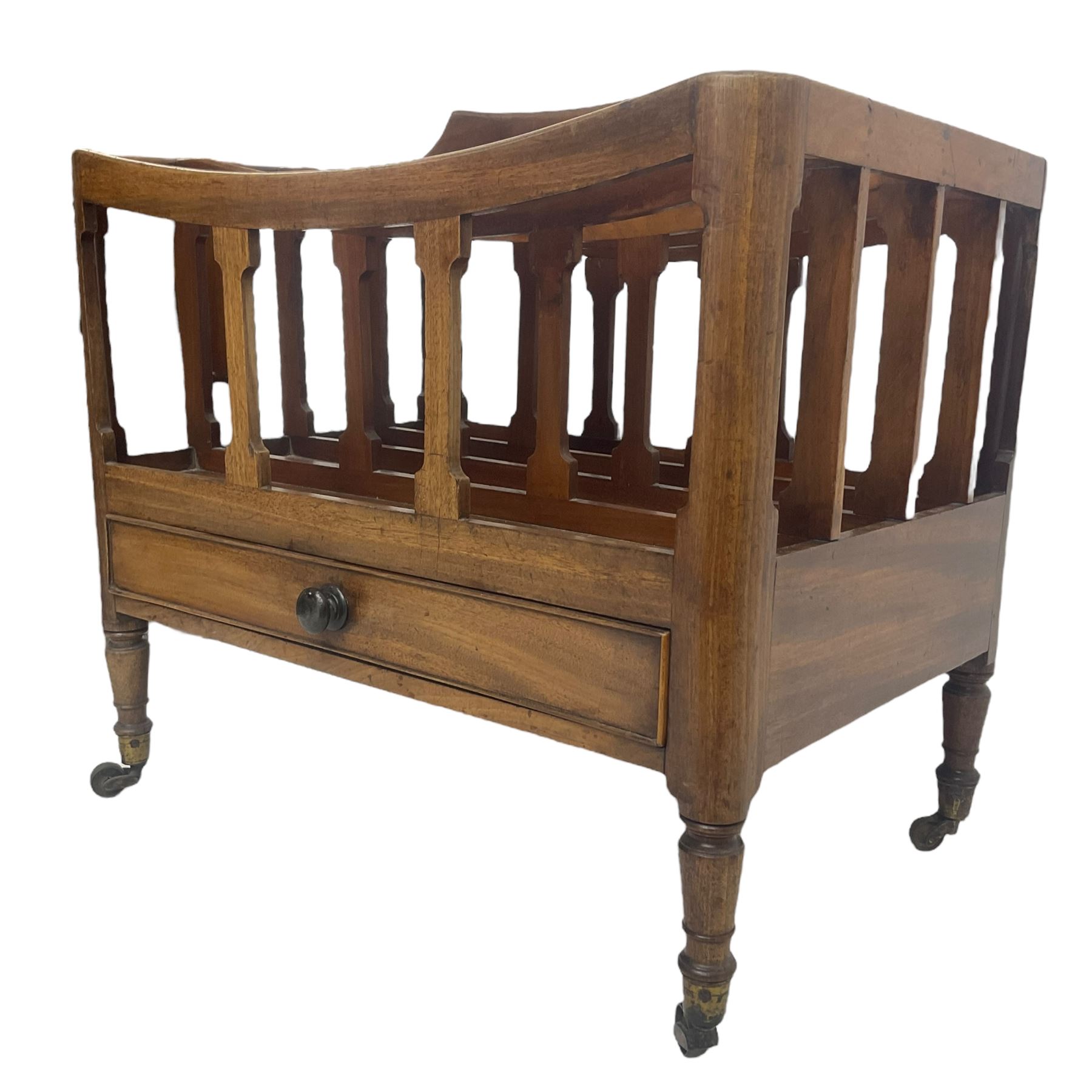 George III mahogany four-division Canterbury, the concave shaped dividers with a central pierced handle, over a single cock-beaded drawer, raised on turned supports terminating in brass cups and castors