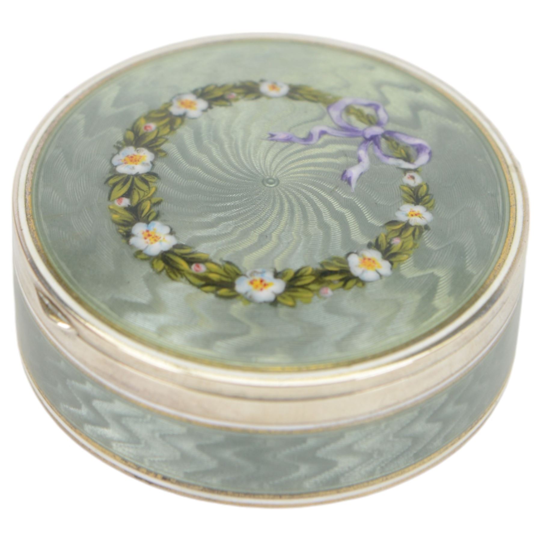 Early 20th century silver and guilloche enamel trinket box, of circular form, decorated throughout with pale green guilloche enamel and a floral wreath to the hinged cover, opening to reveal a gilt interior with personal engraving, import marks for Erich Kellerman, London 1909, D6cm