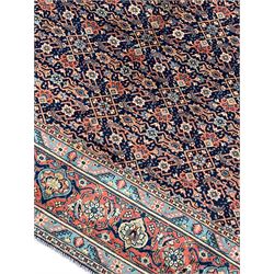 Persian Heratti indigo ground carpet, the busy field decorated with repeating floral pattern Heratti motifs, scrolling leafy branches and palmettes to the crimson ground border, within foliate pattern guard stripes 