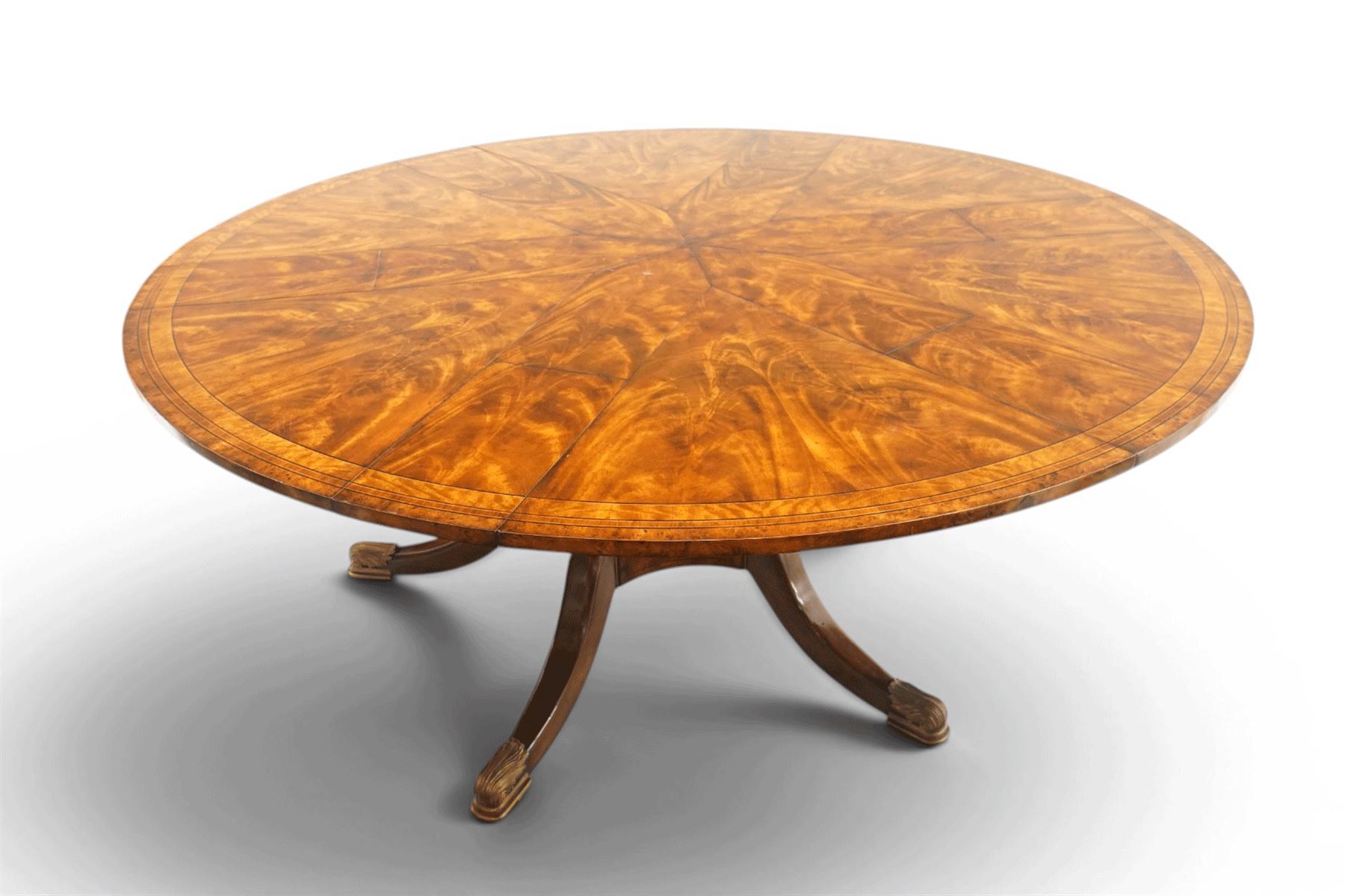 Theodore Alexander - Regency Revival figured mahogany 'Althorp Patent Jupe' extending dining table, the segmented circular top formed of six pull-out triangular divisions with inset fold-out leaves, raised on a large turned vasiform pedestal on a pentagonal platform base with ebonised stringing, terminating to five splayed supports with gilt metal acanthus scrolled feet, retailed by David Hick Interiors, Jersey