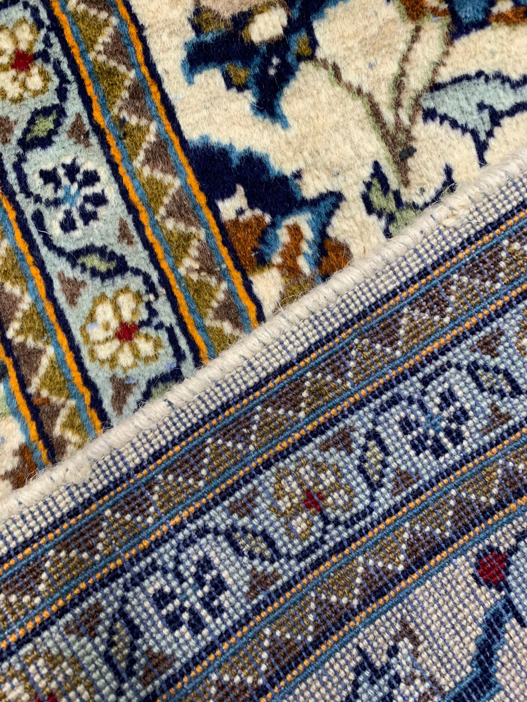 Persian Kashan ivory ground rug, the field decorated with stylised plant motifs and interlacing leafy branches, scrolling border decorated with further plant motifs, floral design guard bands  