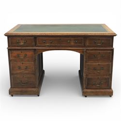Victorian oak pedestal desk, the rectangular top with inset green leather writing panel and decorative gilt border, over a central frieze drawer flanked by two short drawers, twin pedestals each fitted with four drawers with brass handles, arched kneehole opening, standing on moulded plinth bases