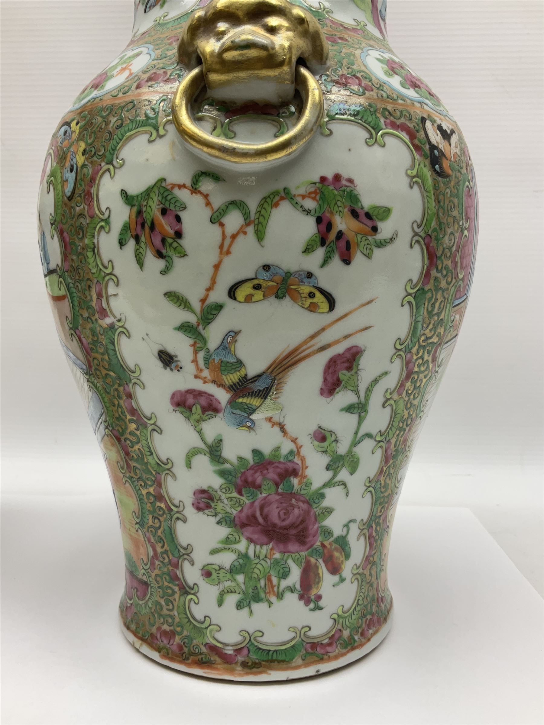 Pair of 19th century Chinese Famille Rose vases and covers, each of baluster form with twin gilt lion mask ring handles to shoulders, the flattened domed covers with gilt temple lion finials, each decorated with alternating reserves of bijin and attendants, and birds and butterflies amongst blossoming peonies, against a gilt ground profusely decorated with stylised scrolls, H32.5cm
