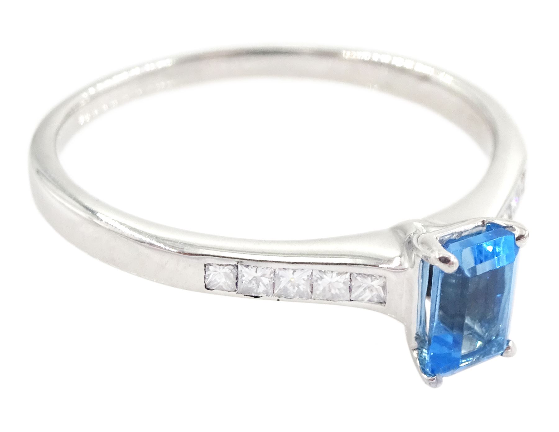 18ct white gold blue topaz and diamond ring, the single emerald cut topaz of approx 0.65 carat, each shoulder set with five, channel set princess cut diamonds