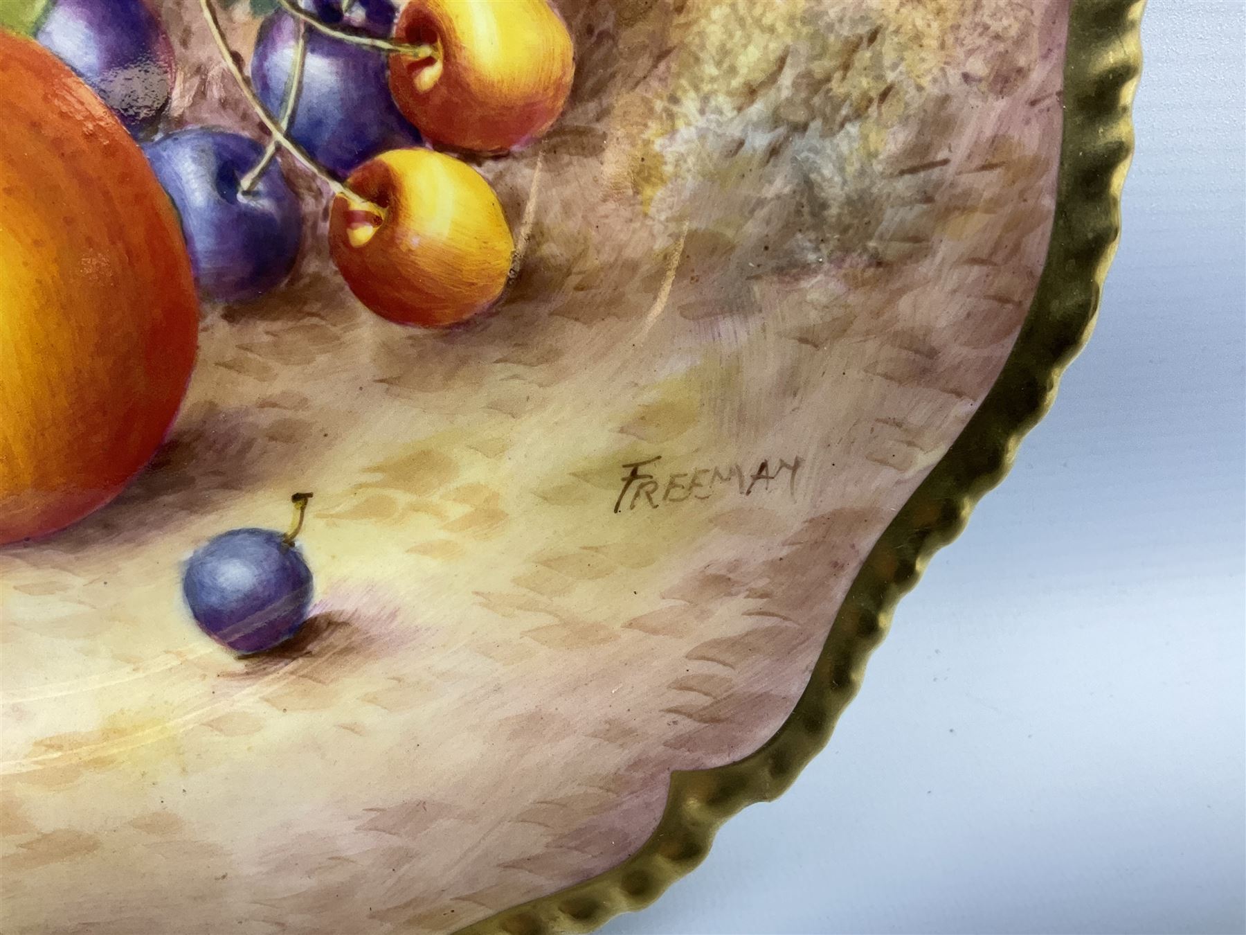 Mid 20th century Royal Worcester cabinet plate decorated by John Freeman, of circular form with gilt shaped rim, hand painted with a still life of fruit upon a mossy ground, signed Freeman, with black printed mark beneath, D27cm