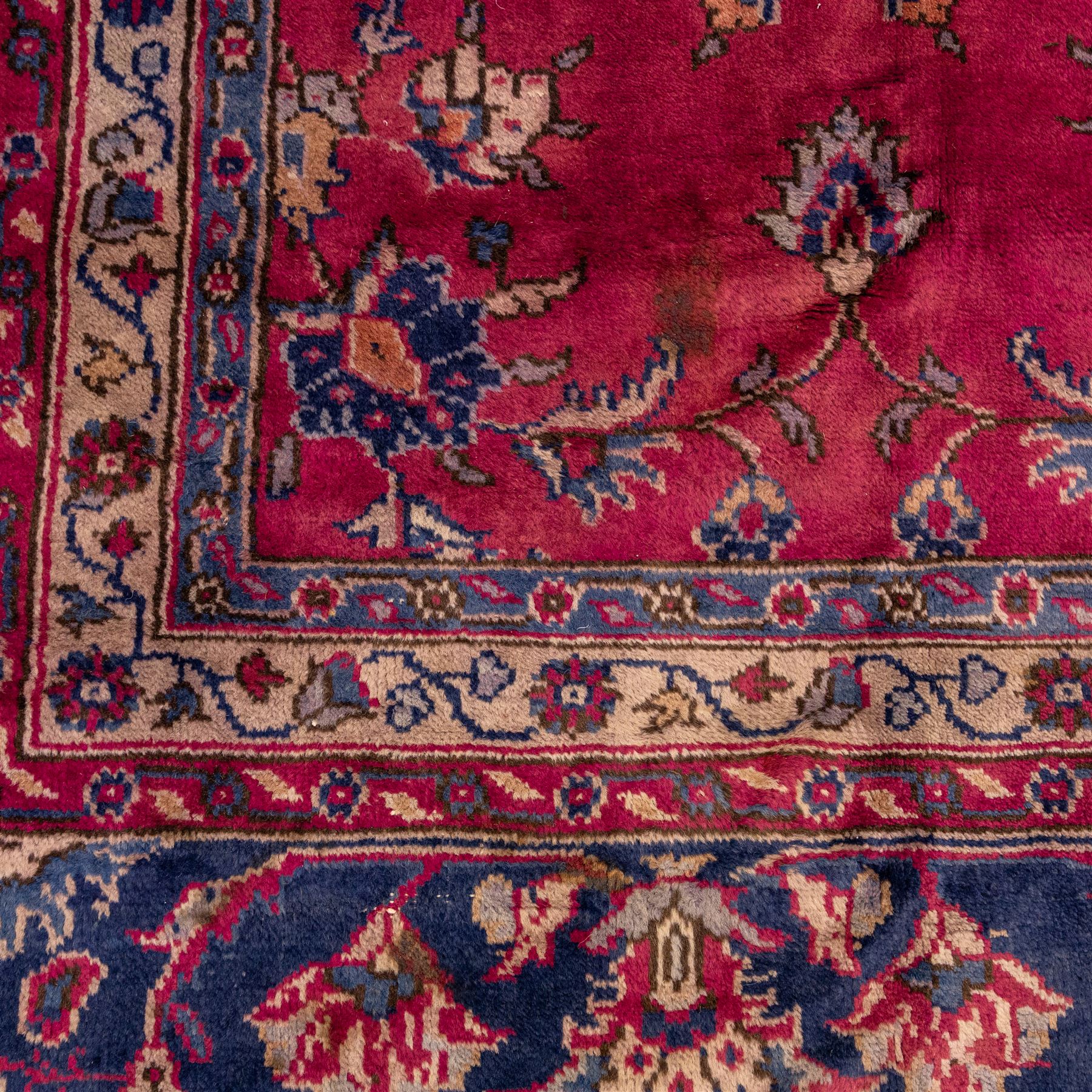 Large Persian-style mahal-type hand-knotted carpet, of rectangular form with a deep crimson field decorated with an all-over arrangement of stylized floral sprays and palmettes, with a central subtle medallion composition enclosed by a dark navy main border of scrolling floral motifs between narrow guard stripes with fringe ends 
