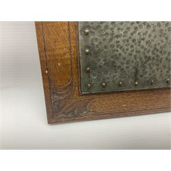 Arts and Crafts oak stand by Arthur Simpson of Kendal, of rectangular form with central hammered pewter panel, surrounded by a border with carved foliate corners, upon two bar supports, bearing label detailed 