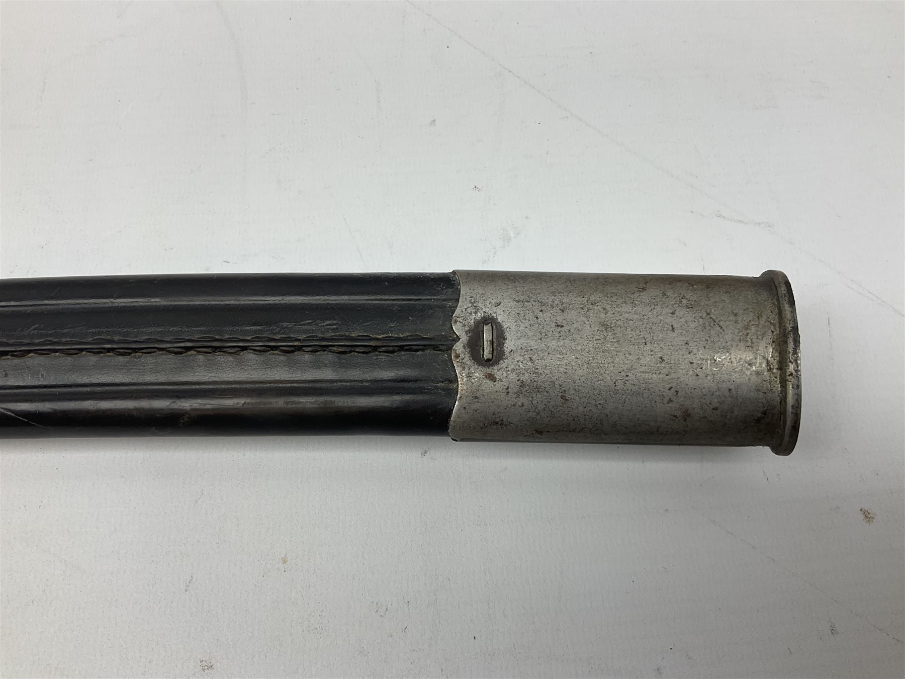 Turkish Model 1874 sword bayonet with 57.5cm curving steel fullered blade and chequered black grip, in steel mounted leather scabbard L75.5cm overall