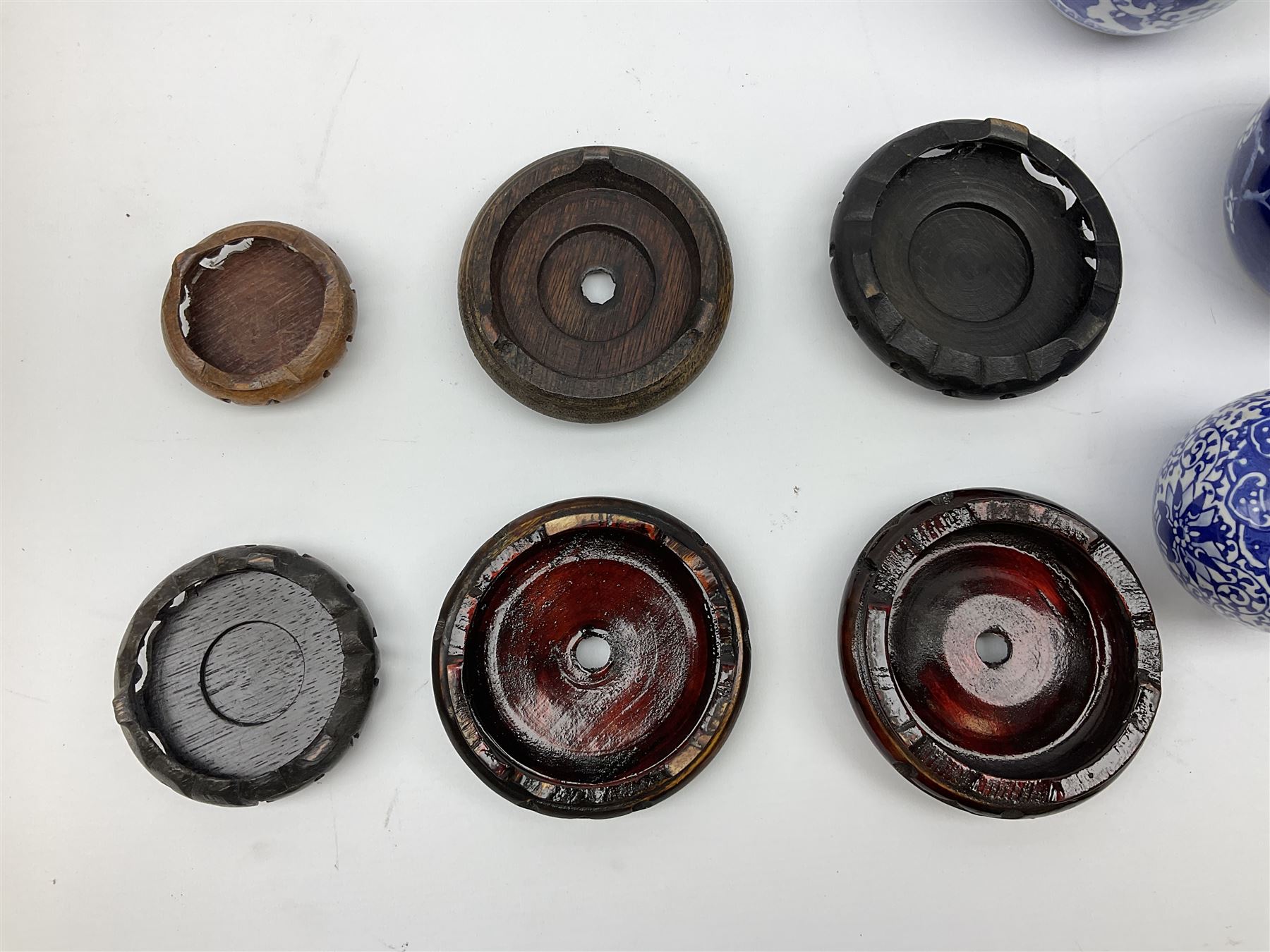 Six Chinese ginger jars, predominantly of blue and white design decorated with blossoming branches, all with lids, housed on various hardwood carved stands, some with character marks beneath