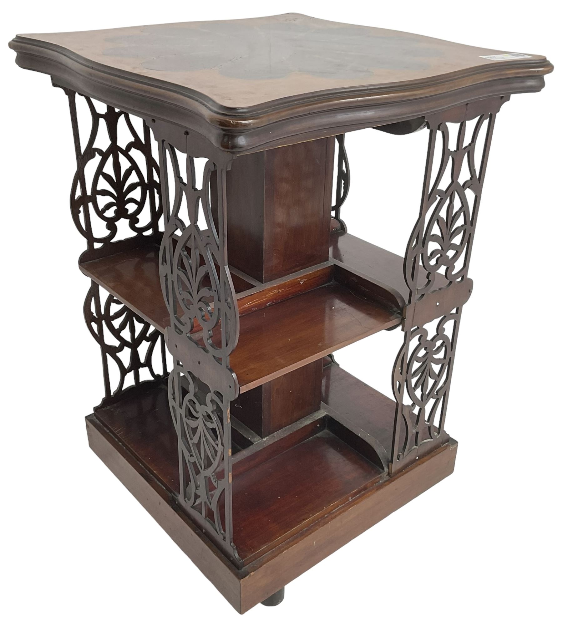Edwardian mahogany revolving bookcase, the shaped moulded top inlaid with cusped panel and trailing bellflowers within a satinwood frame, foliate pierced upright splats and central square column supporting two tiers, on cruciform base with brass and ceramic castors 