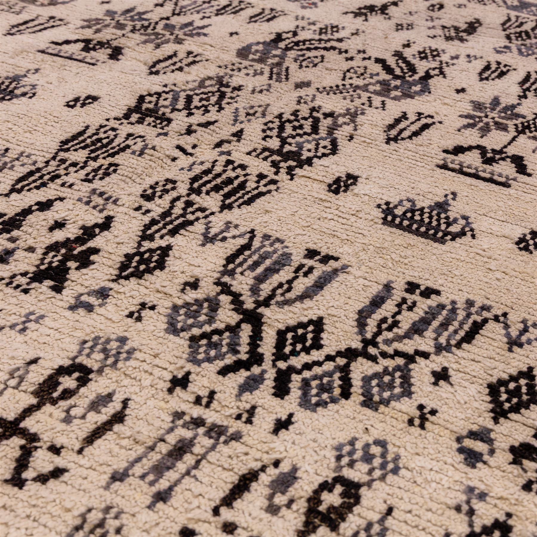 Moroccan hand-knotted Berber rug, of rectangular form, ivory ground woven with horizontal bands of stylized tribal motifs, including abstract animals and anthropomorphic figures, interspersed with geometric devices, with fringe ends 