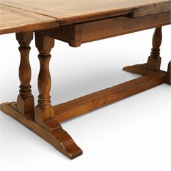 Late 20th century light oak extending refectory table, in the manner of Titchmarsh & Goodwin, rectangular plank top with cleated ends and two draw leaves extending to 260cm, supported on turned end supports united by a stretcher, raised on block feet