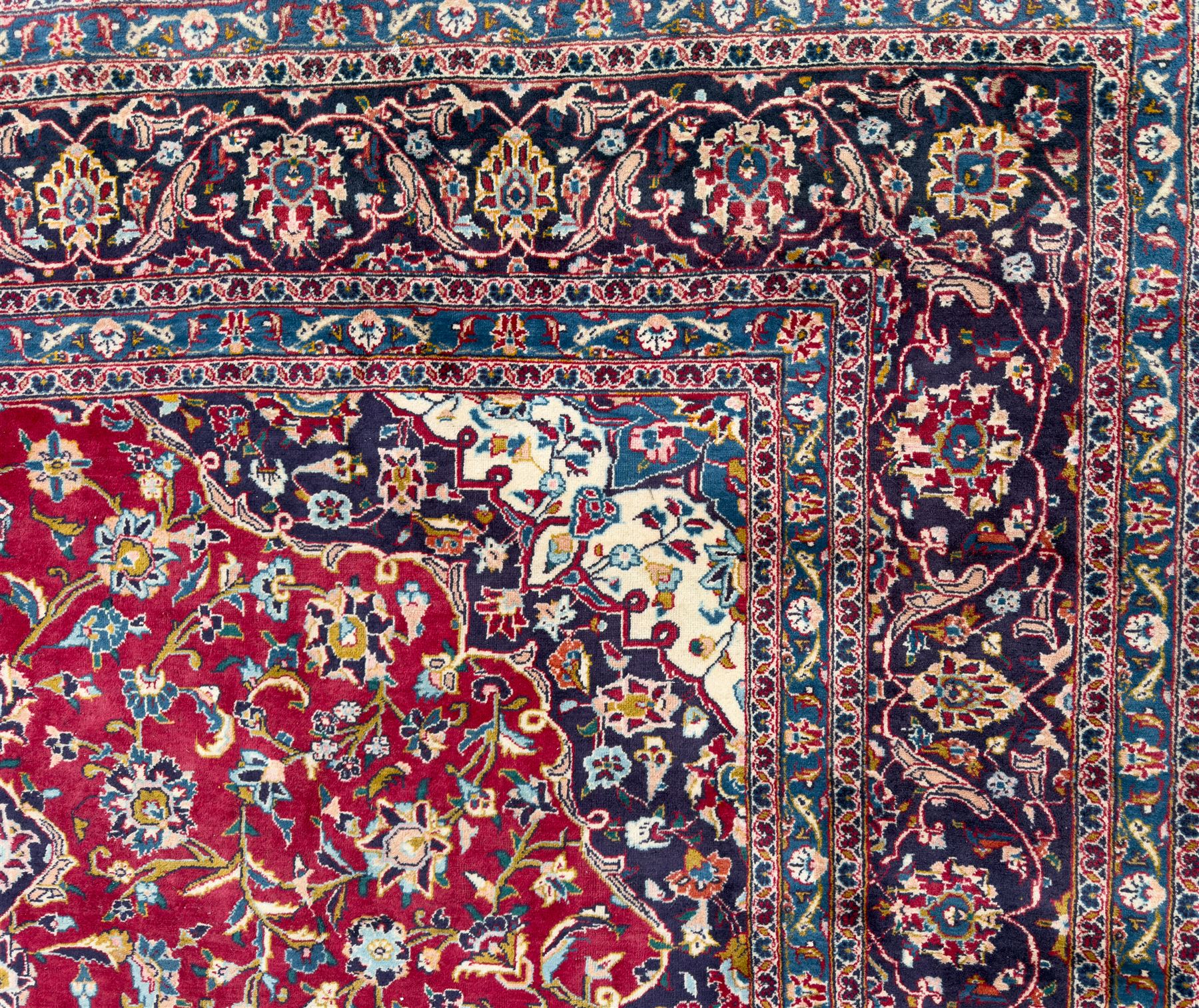 Pair of Persian wool rugs, each with rich red ground, one centred with a diamond-shaped medallion and navy spandrels within a floral field, the other with radiating floral medallion and scrolling foliate motifs, both enclosed by multiple borders with palmette and flowerhead designs, from the region of Kashan 291x376, 299 x 378 