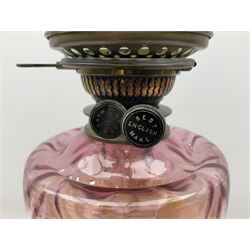 Victorian table oil lamp with black glazed stepped circular base, reeded brass column, moulded pink glass reservoir, duplex burner and frilled rim frosted glass shade with clear glass chimney H69cm