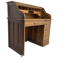 Early 20th century oak roll-top desk, the tambour enclosing pigeon holes and small drawers, the base fitted with slide, a single long drawer and three smaller drawers