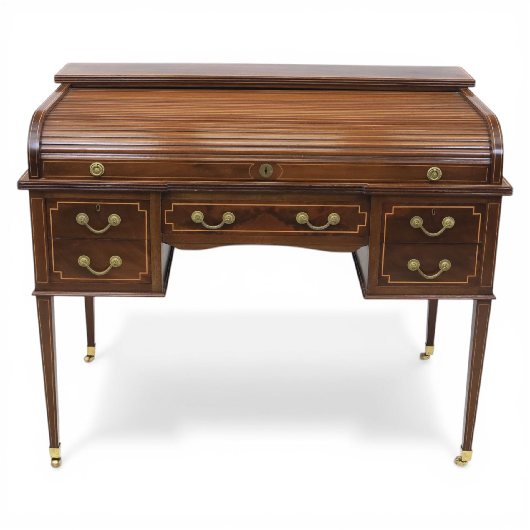 George III style inlaid mahogany tambour desk, the roll top enclosing fitted interior with small drawers and compartments above inset leather writing surface, over three frieze drawers, raised on square tapering supports with brass caps and castors