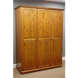  Polished pine triple wardrobe enclosed by panelled doors (W147cm, H190cm, D62cm), matching four drawer chest (W85cm, H90cm, D39cm), and dressing table/desk with six drawers (W139cm, H73cm, D43cm)  