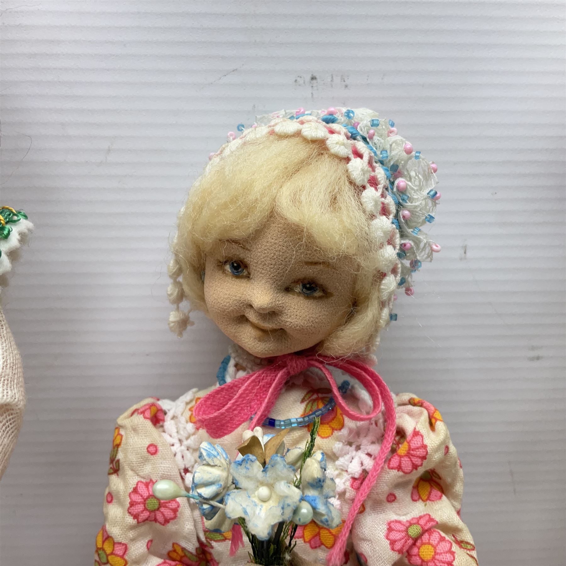 Anna Meszaros Hungary - three hand made needlewrok figurines - each wearing a lon floral dress and bonnet and holding a bouquet of flowers, tallest H32cm (3)  Auctioneer's Note: Anna Meszaros came to England from her native Hungary in 1959 to marry an English businessman she met while demonstrating her art at the 1958 Brussels Exhibition. Shortly before she left for England she was awarded the title of Folk Artist Master by the Hungarian Government. Anna was a gifted painter of mainly portraits and sculptress before starting to make her figurines which are completely hand made and unique, each with a character and expression of its own. The hands, feet and face are sculptured by layering the material and pulling the features into place with needle and thread. She died in Hull in 1998.