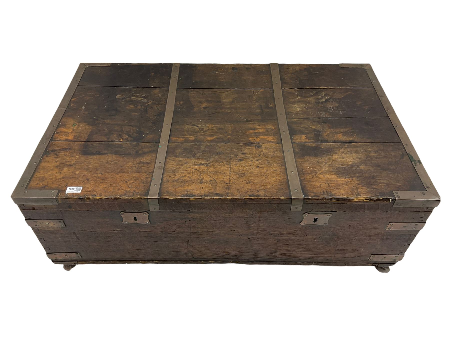 Early 19th century oak low blanket chest, metal strapped and bound, two carrying handles to either end, on castors