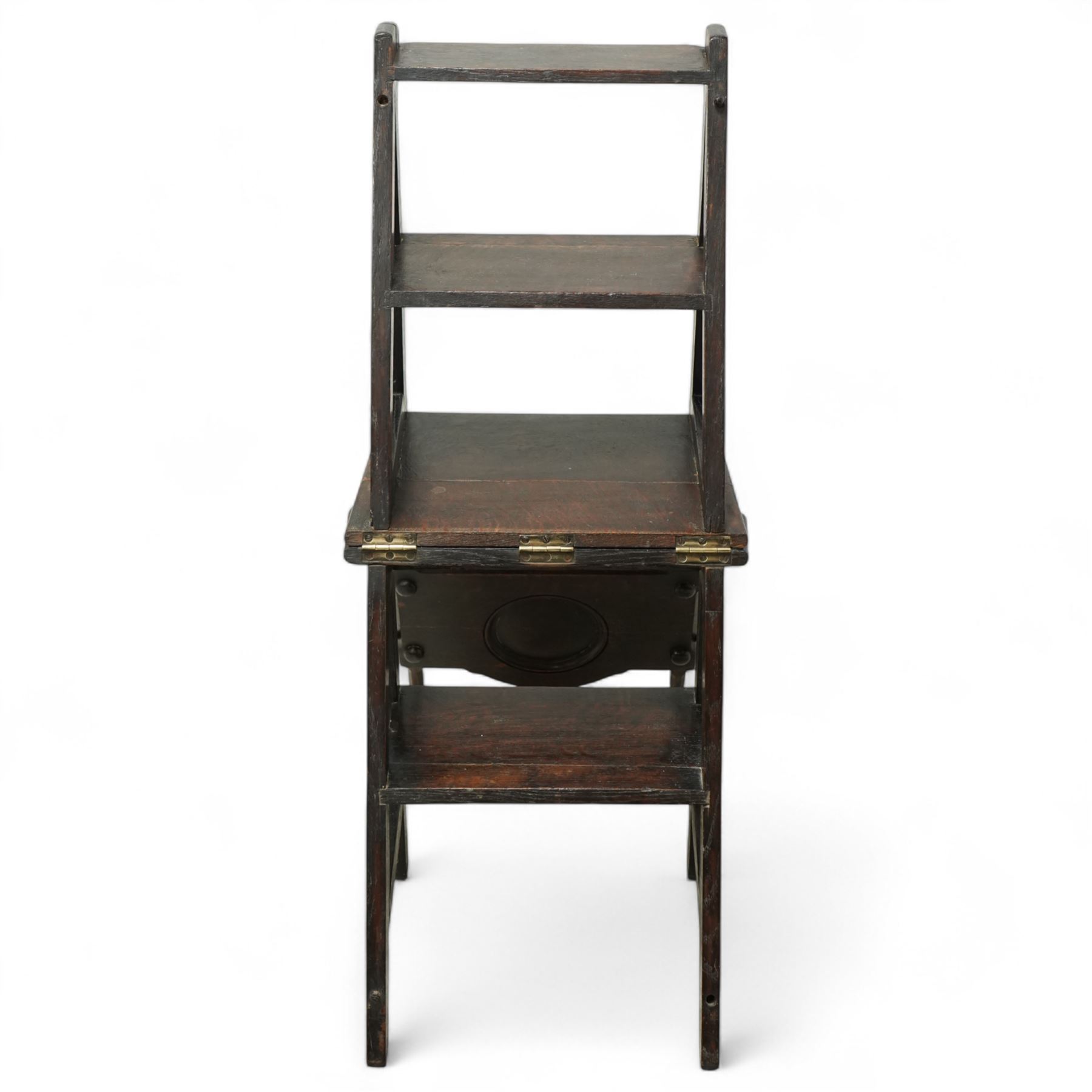 Arts & Crafts oak metamorphic chair, circular panelled back above hinged seat opening into a set of library steps with brass securing straps, circa 1900