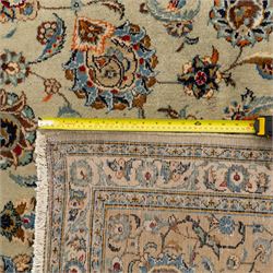 Central Persian Kashan hand-knotted carpet, cream ground with radiating floral rosette medallion in soft blue and terracotta, the field filled with stylised blooms, cloudband vines and palmette motifs, enclosed by triple borders featuring lotus and boteh designs, with cotton fringe ends 