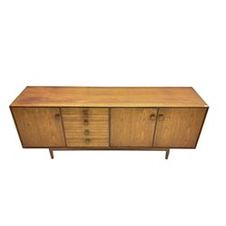 Kofod Larsen for G-Plan - mid-20th century teak sideboard, fitted with four graduating drawers flanked by single and double cupboard enclosing shelves, each with square wooden handles, raised on tapering feet