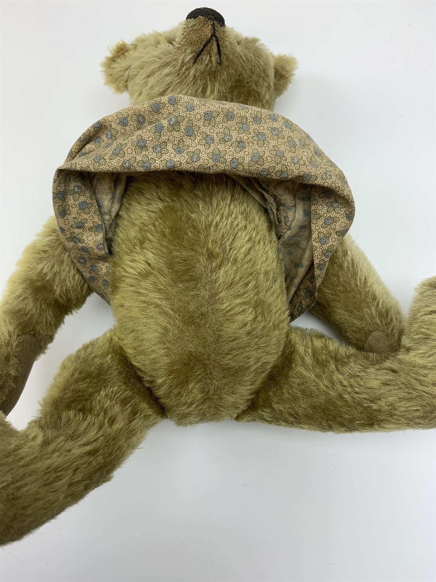 Early 20th century German Steiff teddy bear c1910 with wood wool filled humped back mohair body, swivel jointed head with black boot button eyes and horizontally stitched black nose and mouth, FF metal button to left ear, jointed elongated limbs with felt paw pads and black stitched claws H13