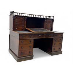 Large Victorian mahogany Registry/Dickens’ desk, spindle gallery top, one side with five small drawers and the other with blind cupboard drawer, revealing pigeon holes with scroll carved locking side bars on either side, above a hinged and leathered writing slope with three drawers and pigeon holes underneath, above a central locking drawer with key, the pedestals each with four drawers and  turned knob handles, separates into four parts for transport