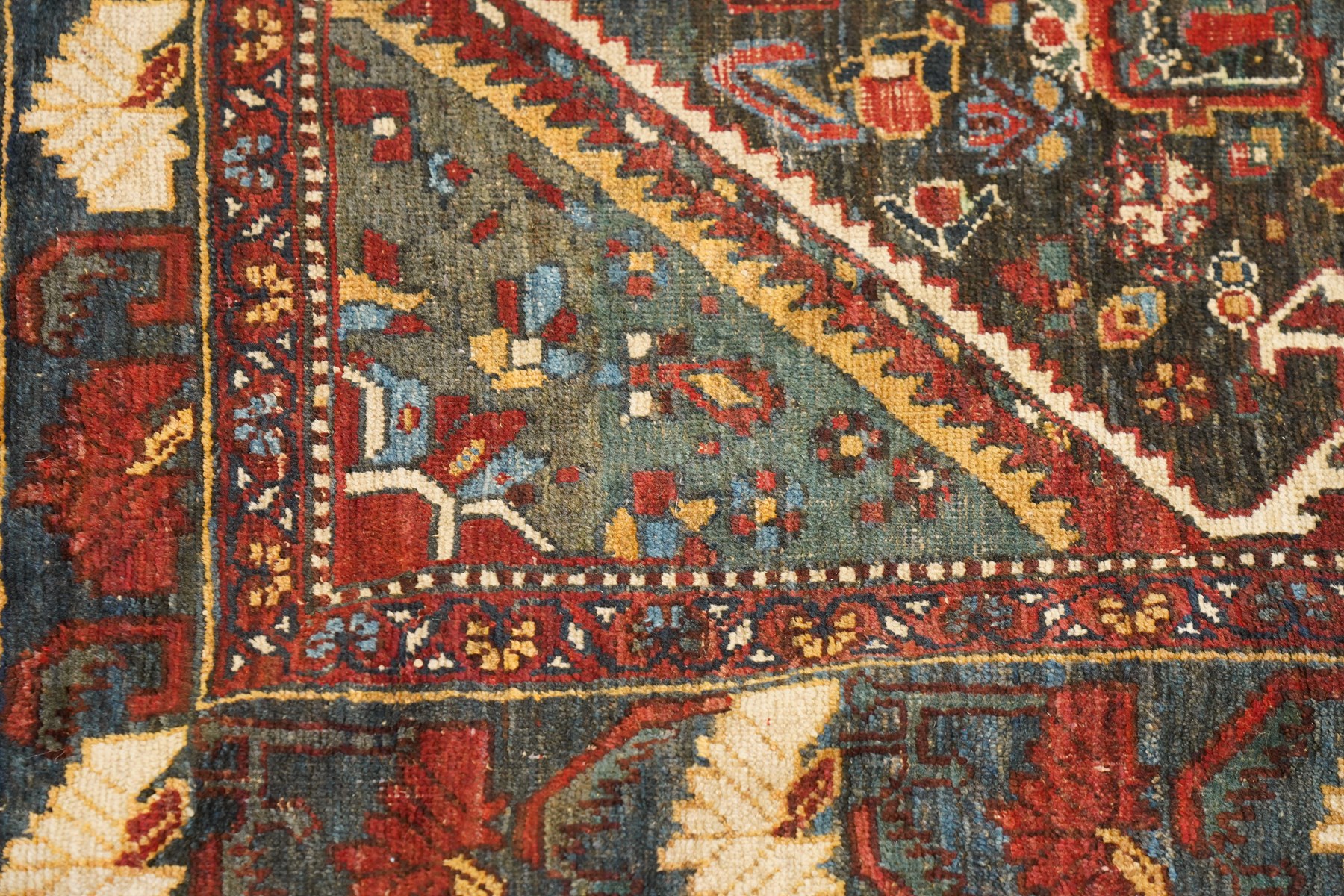 Antique Persian Qashqai dark indigo ground tribal rug, the busy field decorated with a geometric triple pole medallion surrounded by numerous stylised plant motifs with contrasting cyan spandrels, the multiple guard bands woven with stylised palmettes and foliage