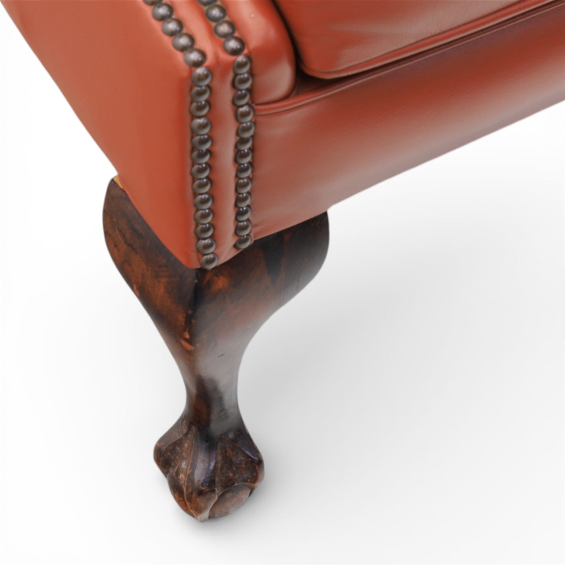 Georgian design red leather wingback armchair, with shaped back and scrolled arms, and close brass studded trim, upon cabriole front legs with claw and ball feet