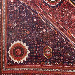Qashqai wool carpet, red diamond-shaped field decorated with three stepped pole medallions, floral rosettes and scattered stylised motifs, within dark blue spandrels and multiple geometric guard borders