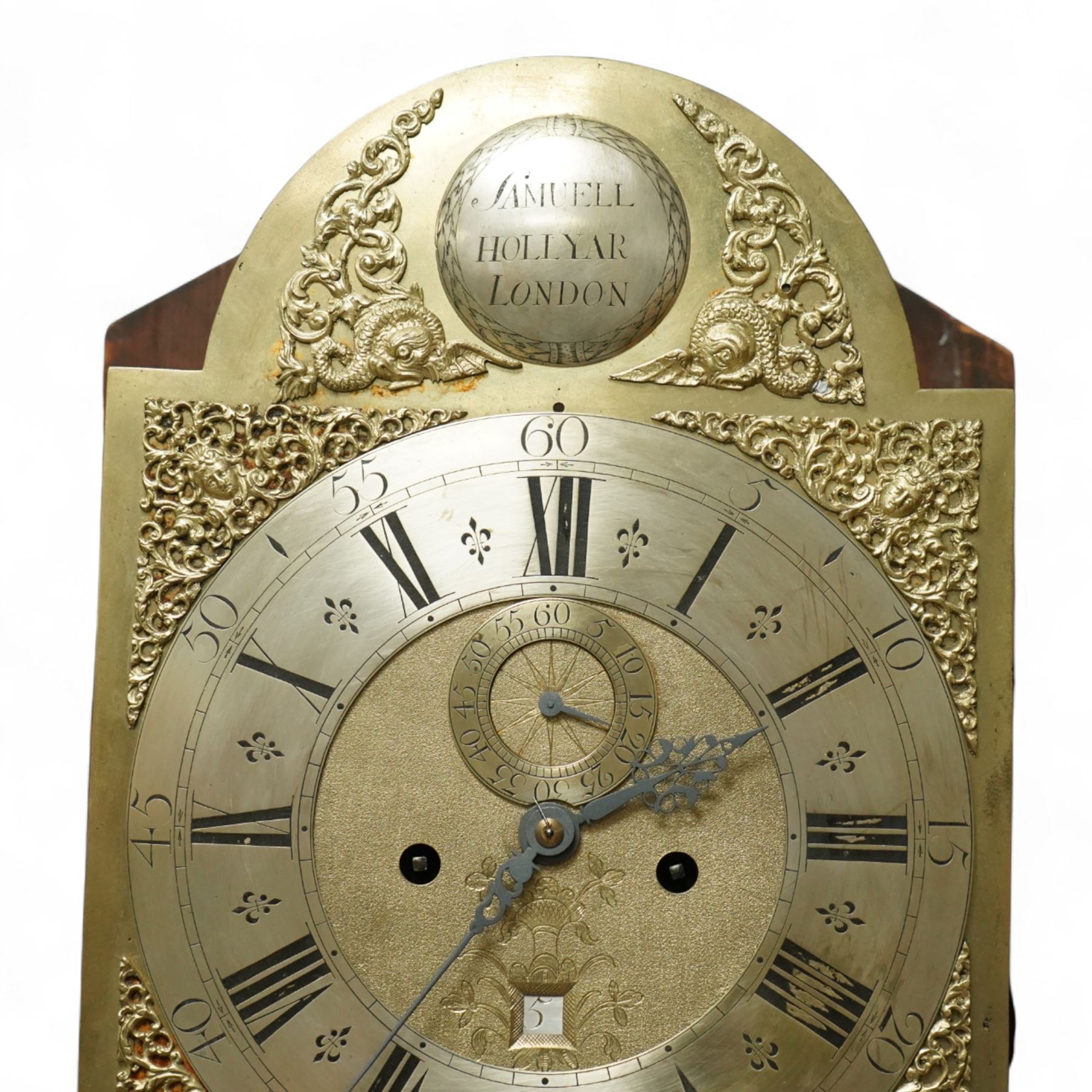 Samuell Hollyar of London - mid-18th century, figured mahogany Longcase clock with a swan neck pediment and brass parterre, with glass panels to the sides and reeded pilaster flanking the hood door, conforming recessed pillars to the trunk and a wavy toped door with  inlay, square plinth raised on bracket feet, With a brass dial with cast spandrels and makers name to the arch, matted dial centre with steel hands, seconds dial and date aperture, silvered chapter with Roman numerals, five minute Arabic's, minute and inner quarter hour tracks, dial pinned to an 8-day rack striking movement, sounding the hours on a bell. With weights and pendulum.
Samuel Hollyar is recorded as being apprenticed in London in 1683 and a member of the clockmakers company 1705-20.