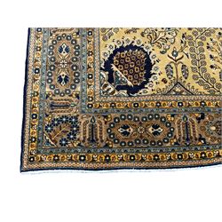 Persian Qom pale gold ground rug, profusely decorated with intricate patterns, lozenge central medallion decorated with trailing leaves and flower heads, surrounded by curled leaf branches and flower head motifs, the spandrels decorated with floral urns, multiple band border, the main band decorated with repeating geometric and flower motifs