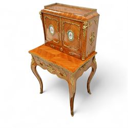 Late 19th century French Louis XV style kingwood and ormolu mounted bonheur du jour, the upper section with a pierced three-quarter gallery over a pair of cupboard doors inset with Sèvres-style porcelain portrait plaques, enclosing a shelved interior over two short drawers, the serpentine top and apron richly mounted with gilt-bronze foliate and scroll motifs, single frieze drawer below on cabriole supports with acanthus cast sabots