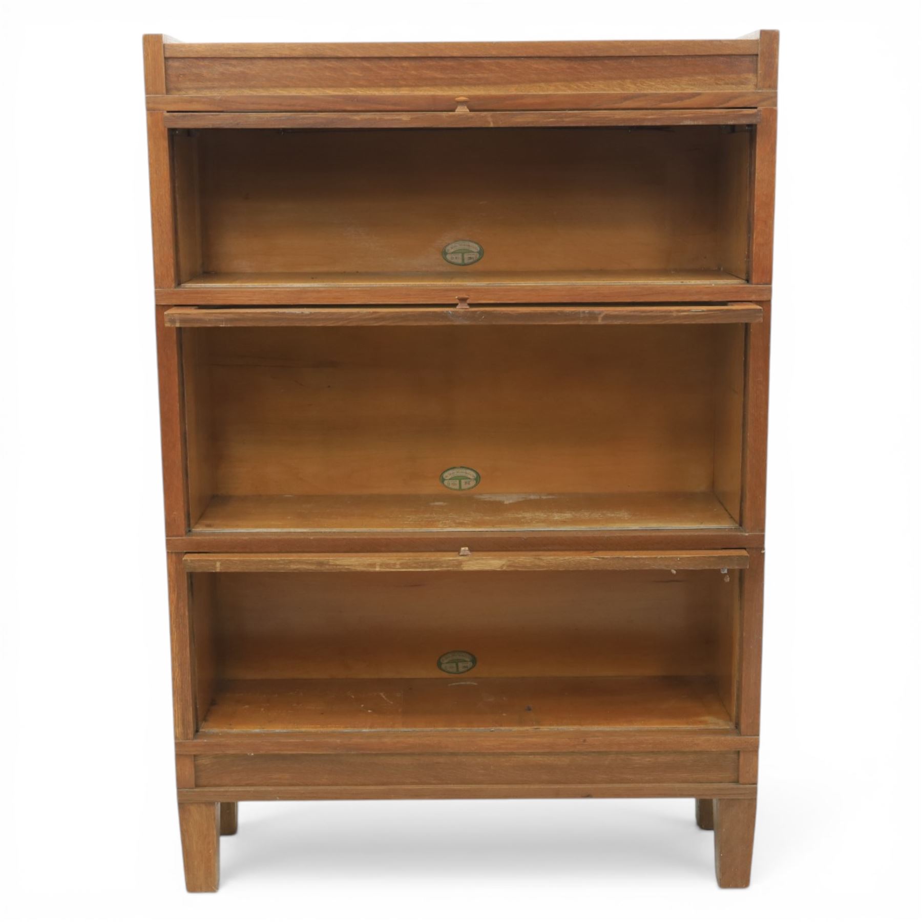 Globe Wernicke - Modular oak sectional bookcase, the three glazed up-and-over doors with panelled sides, raised on a plinth base with square supports