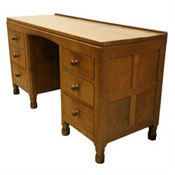 Mouseman - adzed oak kneehole dressing table or desk, the rectangular adzed top with raised back and canted corners, over an arched recessed kneehole flanked by three graduating drawers to each side with turned knob handles, raised on octagonal feet, with carved mouse signature, by the workshop of Robert Thompson of Kilburn