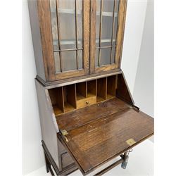 Early 20th century oak bureau bookcase, raised display cabinet enclosed by glazed doors, fall front above two drawers, turned supports joined by plain stretchers