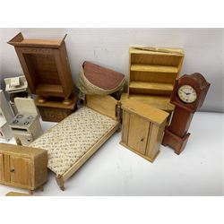 Quantity of wooden doll's house furniture for kitchen, living room and bedroom including chaise longue, longcase clock, bureau, tables, beds, dressing tables, sink unit, cookers etc; various scales; mainly natural wood finish but some painted