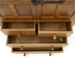 Mouseman - mid-20th century adzed and panelled oak tallboy chest, arcade carved cresting rail over two panelled cupboard doors with wrought iron fittings and latch, enclosing single shelf, over two short and two long drawers with lightly adzed facias and turned knob handles, raised on square supports, relief carved mouse signature, by the workshop of Robert Thompson of Kilburn