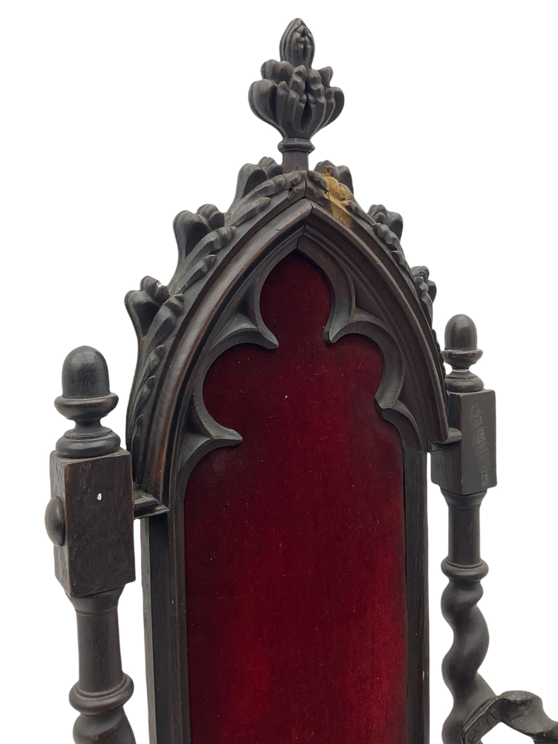 Victorian oak and wrought metal Gothic open armchair, the pointed arched back carved with foliate, cusped inner arch upholstered in red, spiral turned uprights and supports, with arms made of spiral forged metal