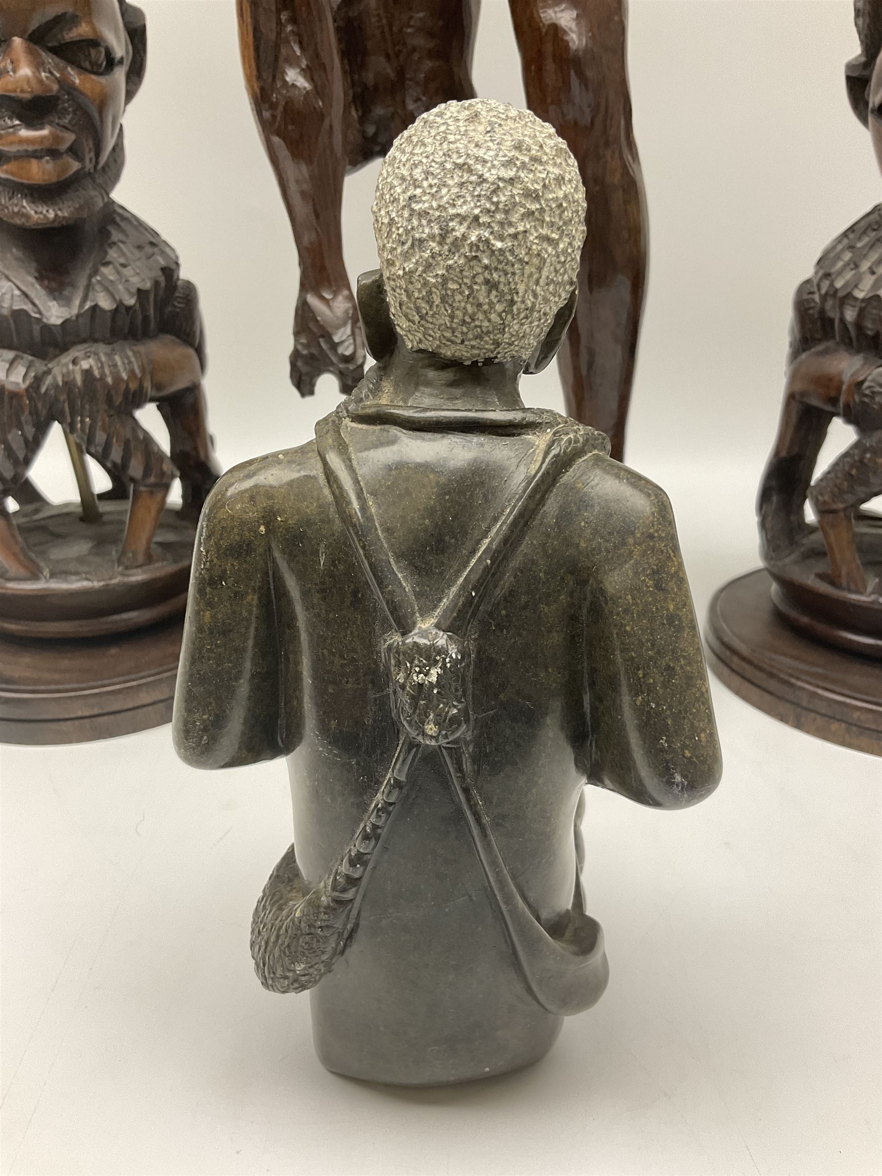 Pair of 20th century carved wood table lamp with African busts and figures, together with a carved wooden figure and soapstone figure, lamps H44cm