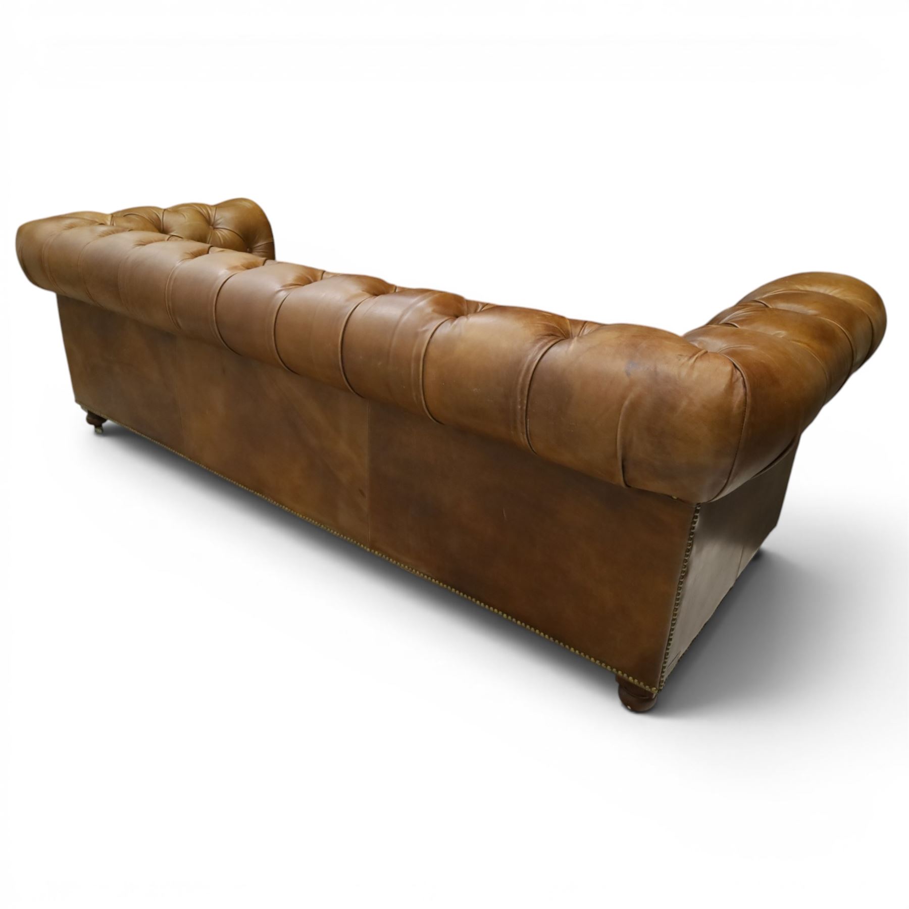 Timothy Oulton for HALO - Three seater brown leather chesterfield sofa, with button back and arms, with two loose cushions, raised on a dark stained supports terminating in castors 