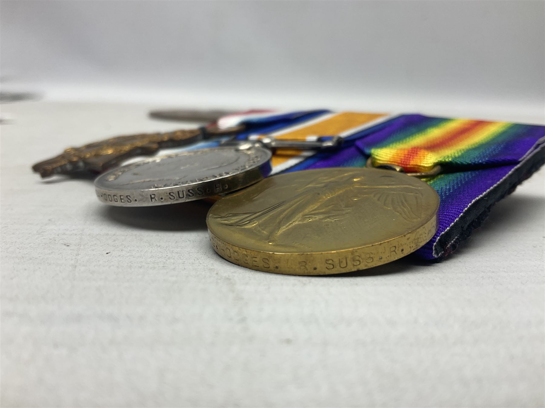 WW1 KIA group of three medals comprising British War Medal, 1914-15 Star and Victory Medal together with bronze Memorial Plaque named to G-13 Pte. F.G. Hodges R. Suss. R.; with ribbons; displayed on modern board for wearing; some biographical details