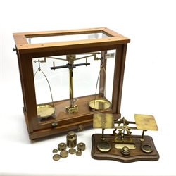 Set of brass laboratory scales by Philip Harris Birmingham in glazed mahogany cabinet with upward sliding front door and quantity of loose brass weights  W39cm H38cm; together with a set of late 19th century brass postal scales on mahogany serpentine base with inset weights W25cm (2)